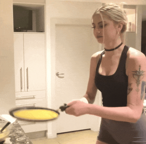 a woman with a tattoo on her arm is holding a pan of food