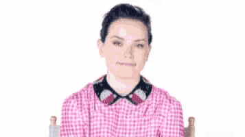 a woman in a pink shirt is sitting in a chair .