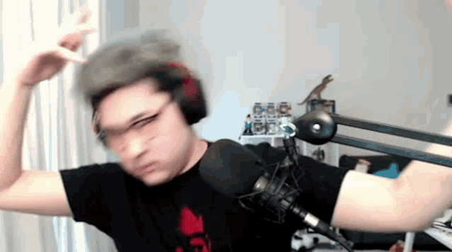 a man wearing headphones is standing in front of a microphone in a room .