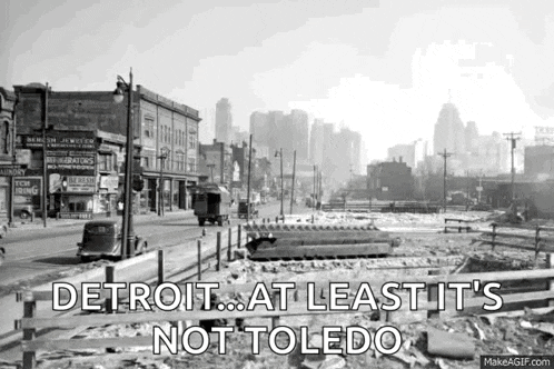a black and white photo of a city street with the words `` detroit ... at least it 's not toledo ''
