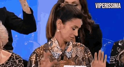 a woman in a leopard print shirt is sitting in a chair with her hands up .