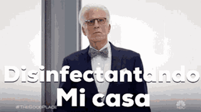 a man in a suit and bow tie is standing in front of a window and says disinfectando mi casa .