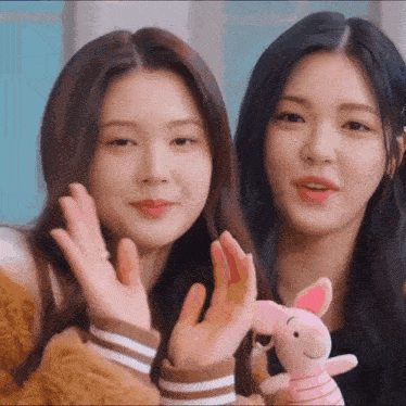 two girls are standing next to each other holding stuffed animals .