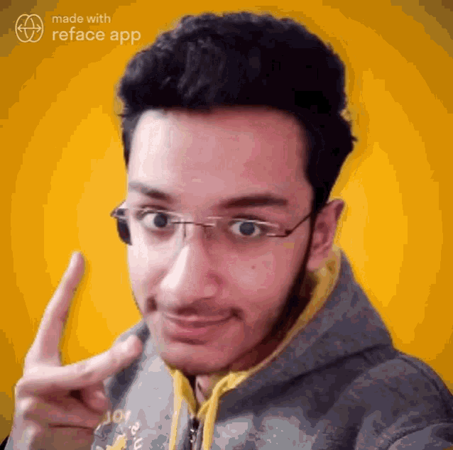a man wearing glasses and a hoodie is pointing up