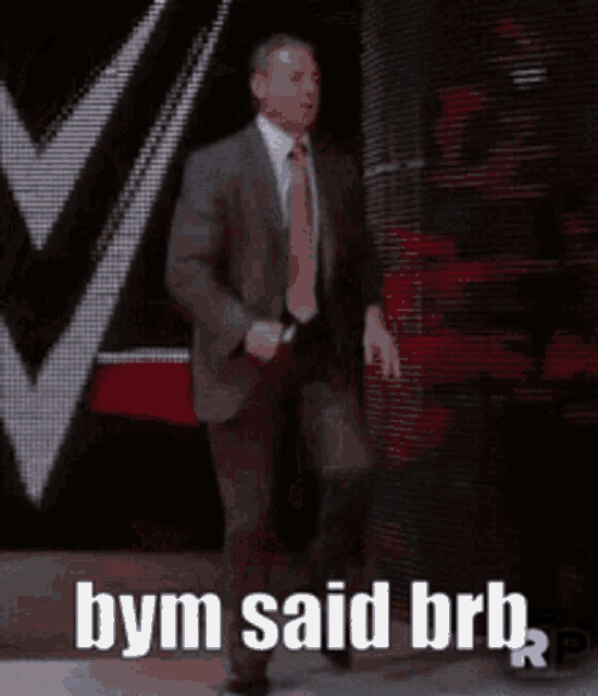 a man in a suit and tie is walking on a stage with the words bym said brb written below him