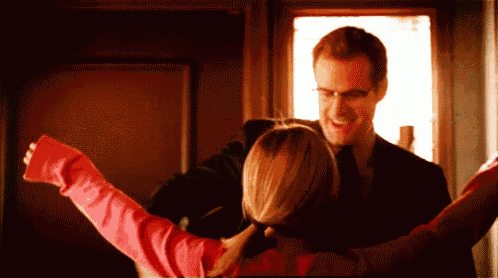 a man in a suit and tie is hugging a little girl in a pink shirt