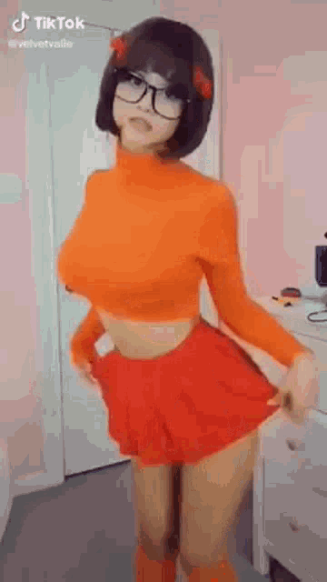 a woman in a costume is standing in a room wearing glasses and a red skirt .