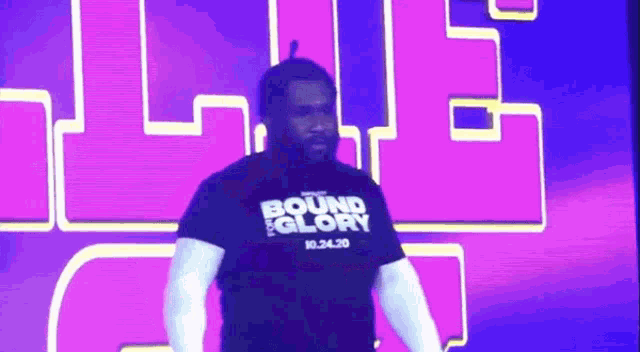a man wearing a bound glory t-shirt stands in front of a purple background