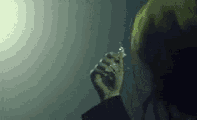 a close up of a person holding a cigarette in their hand in a dark room .