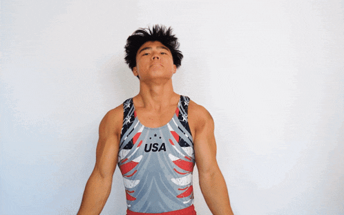 a young man wearing a usa leotard is standing with his arms outstretched