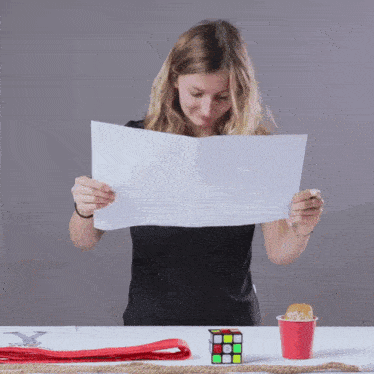 a woman is reading a piece of paper next to a red cup of popcorn