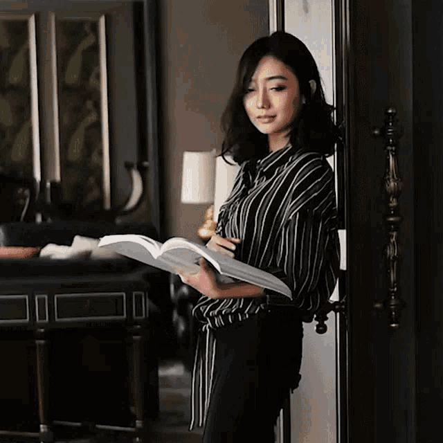 a woman in a black and white striped shirt holds a book