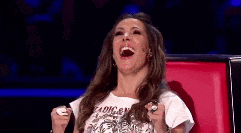 a woman is laughing while sitting in a chair with her mouth open and her hands in the air .