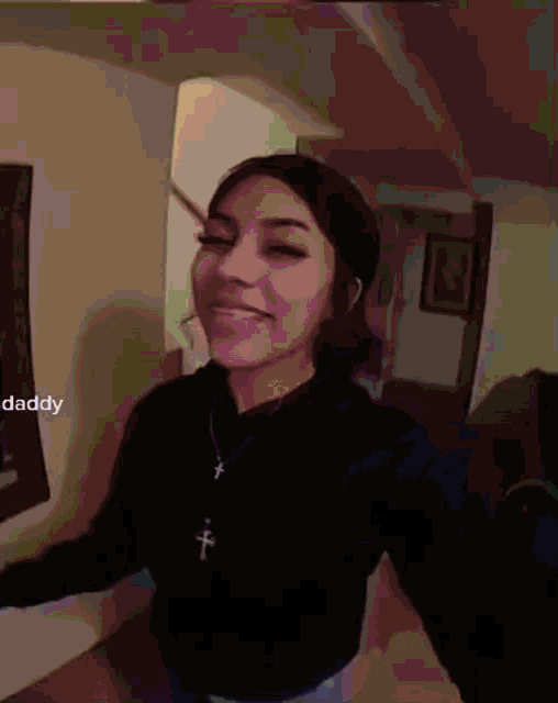 a girl wearing a black sweater and a cross necklace with the word daddy on the bottom