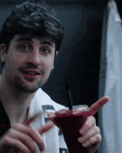 a man with a beard is holding a martini glass with a straw in it .