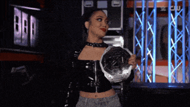 a woman is holding a wrestling championship belt in front of a wwe logo