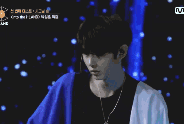 a man in a blue jacket stands in front of a blue curtain that says ' into the land ' on it