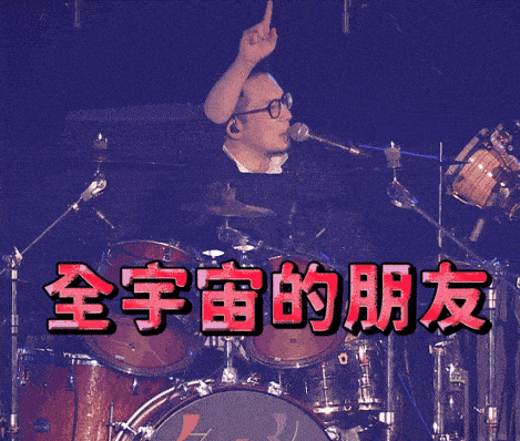 a man singing into a microphone in front of a drum set with chinese writing on it