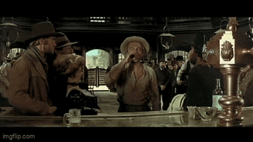 a man in a cowboy hat sits at a bar talking to a woman