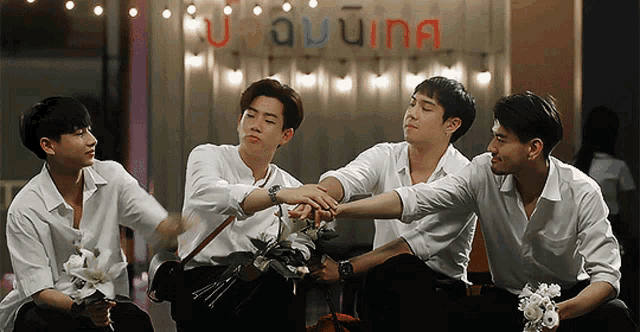 a group of young men are sitting in front of a sign that says " u aunina "