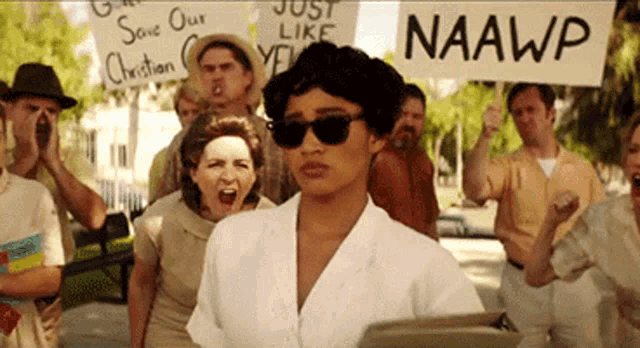 a woman holding a sign that says naawp stands in front of a crowd of people