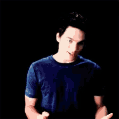 a young man in a blue shirt is making a funny face with his hands outstretched