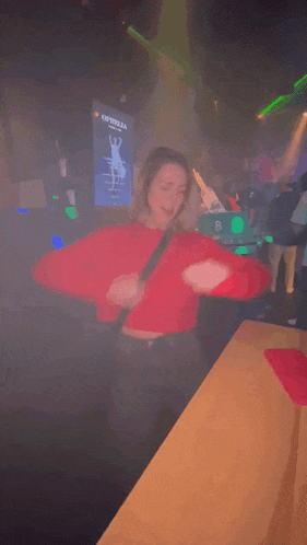 a woman in a red sweater is dancing in a dark room