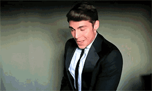 a man in a tuxedo and tie is looking down