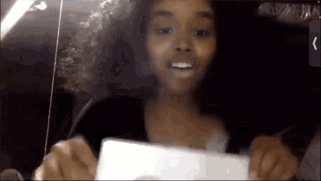 a girl with curly hair is holding a piece of paper and smiling