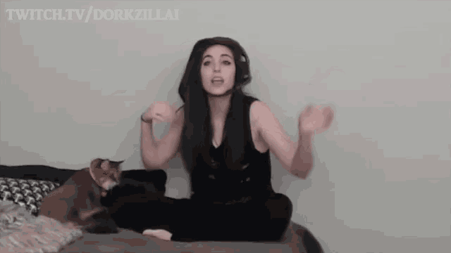 a woman is sitting on a bed next to a cat and talking .
