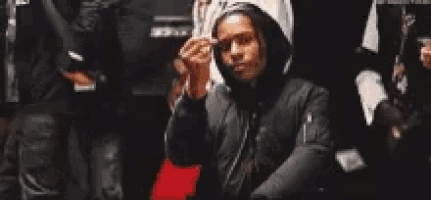 a man in a hooded jacket is smoking a cigarette .