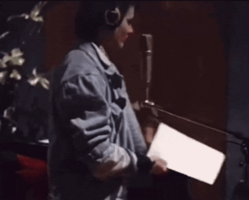 a woman in a blue jacket is singing into a microphone