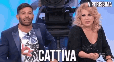 a man and a woman are standing in front of a camera with the word cattiva written on the bottom