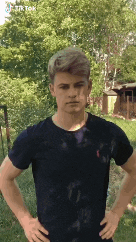 a young man in a black t-shirt is standing with his hands on his hips and a tiktok logo above him