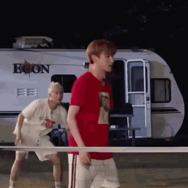 two men are playing tennis in front of a trailer that says econ