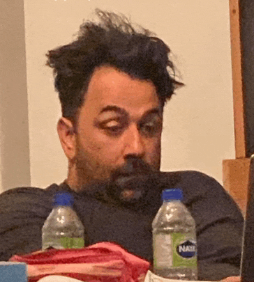 a man sits at a table with two bottles of natl water on it