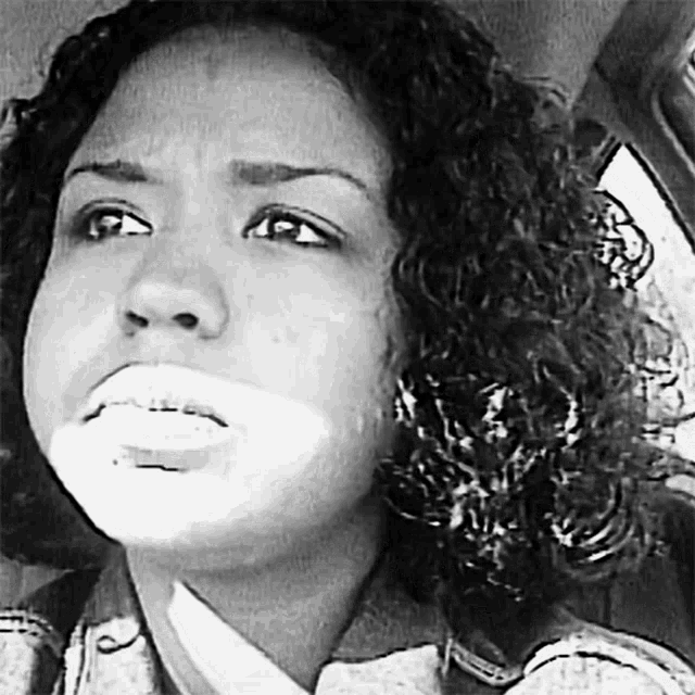 a black and white photo of a woman with curly hair making a face