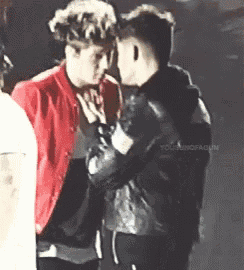 a man in a red jacket is touching another man 's face