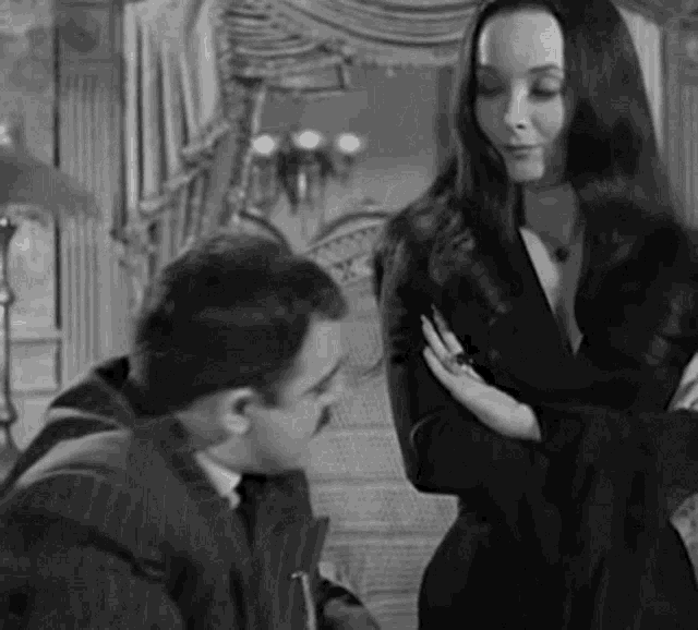 a black and white photo of a man and a woman standing next to each other in a living room .