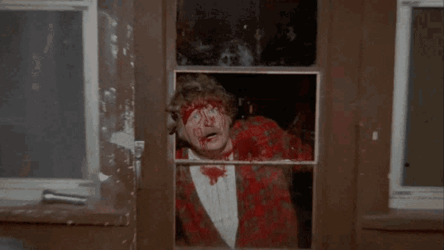 a man with blood on his face looks through a window