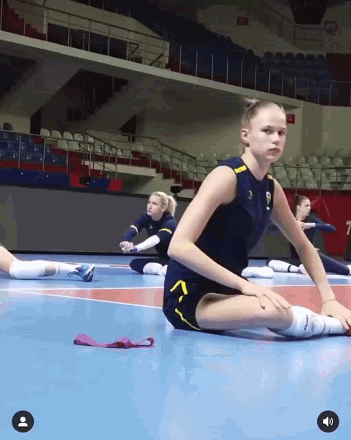 a female volleyball player stretches on the floor