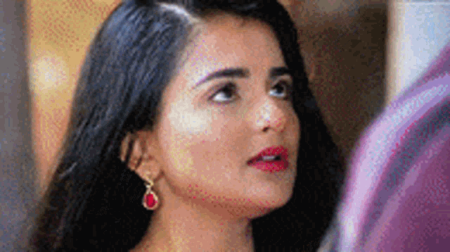 a close up of a woman 's face wearing red earrings and red lipstick .