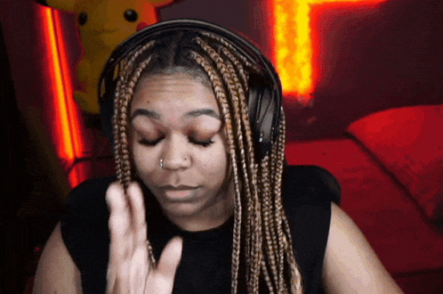 a woman with braids wearing headphones making a gesture