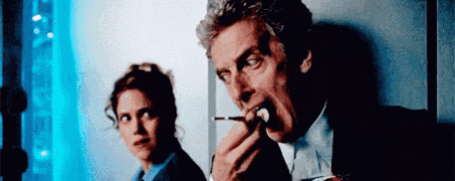 a man and a woman are standing next to each other . the man is eating something while the woman is looking on .