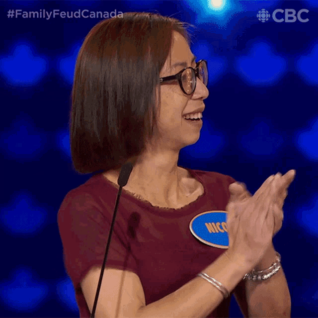a woman wearing glasses and a name tag that says nico is clapping her hands