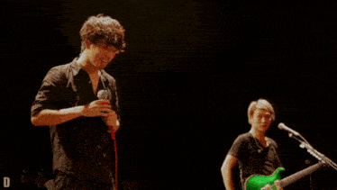 a man singing into a microphone while another man plays guitar