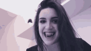 a woman with long hair is smiling and looking at the camera with her mouth open .