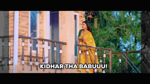 a woman in a yellow saree stands on a balcony with the words kidhar tha babuuu