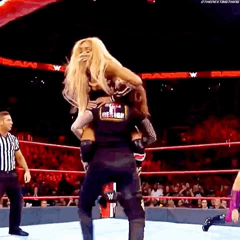 a man is carrying a woman in a wrestling ring .