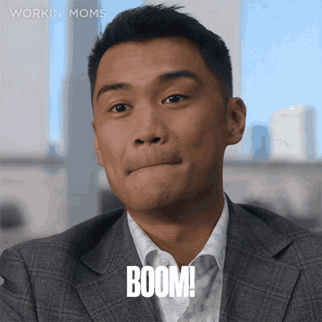 a man in a suit says boom in front of a workin ' moms logo